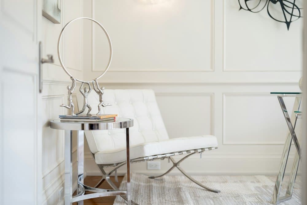 White lounge chair beside a vanity mirror