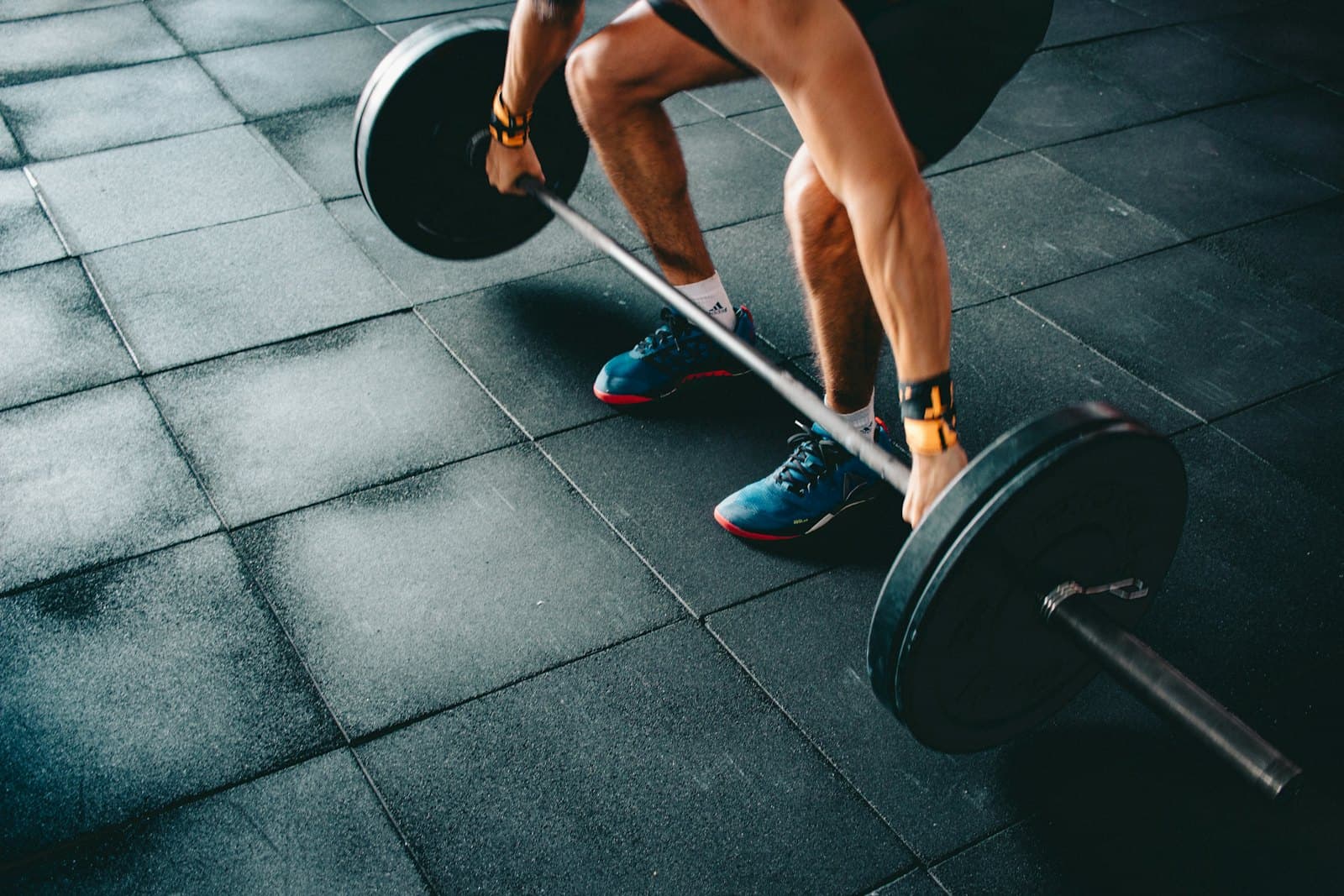 Athlete gripping a loaded barbell on a gym floor
